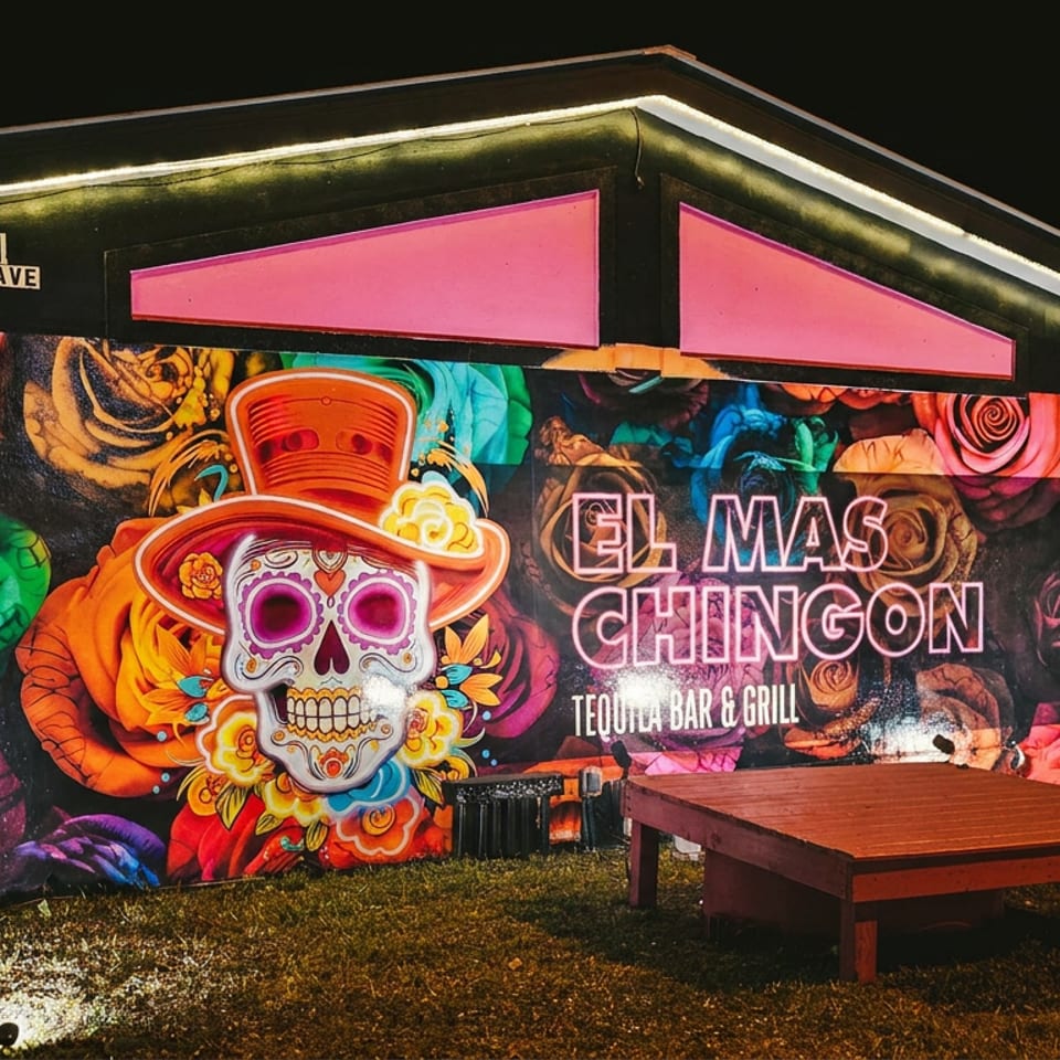 El Mas Chingon Tequila Bar & Grill exterior at night, with a colorful mural and neon sign.